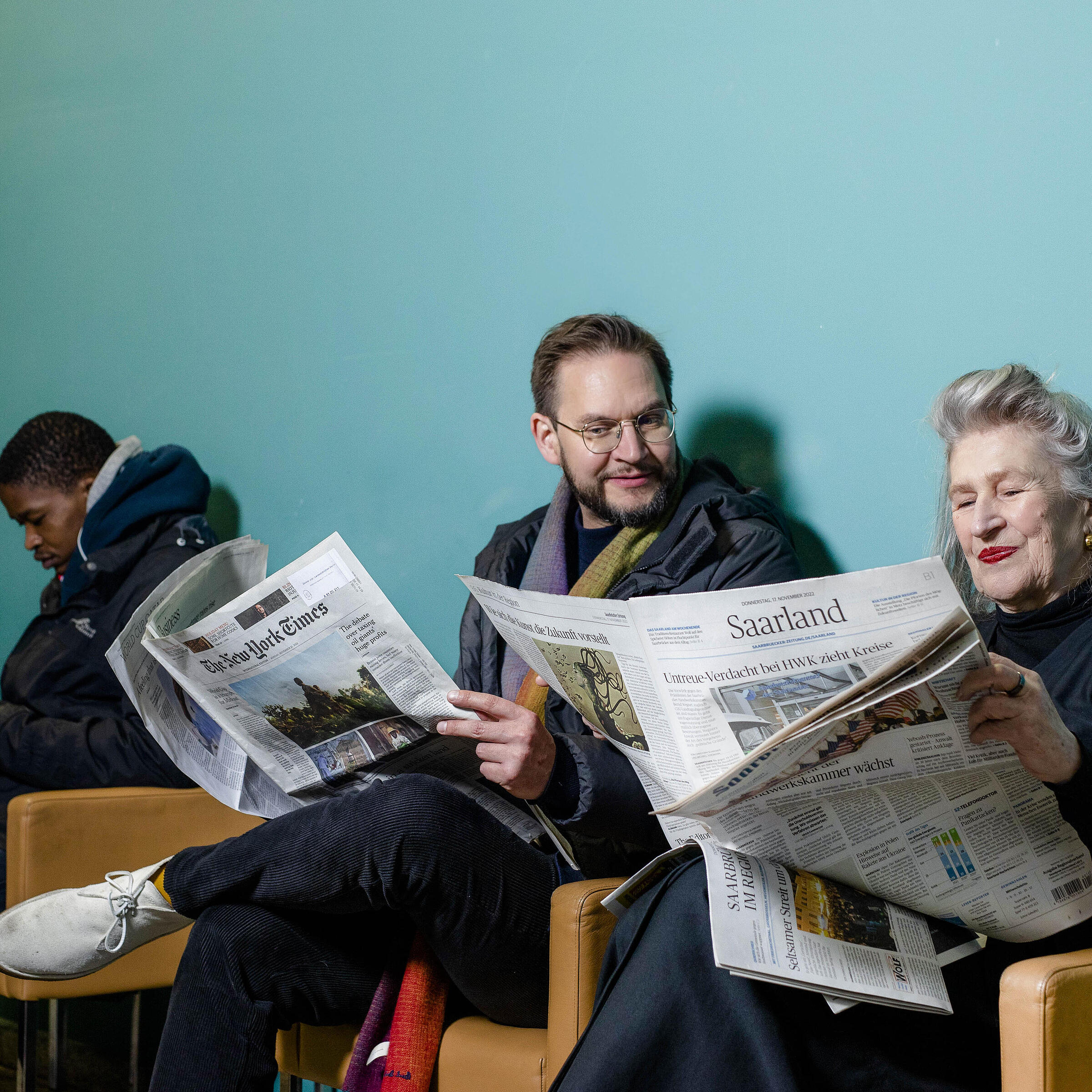 Menschen sitzen auf Sesseln und lesen Zeitung in Berliner Stadtbibliothek