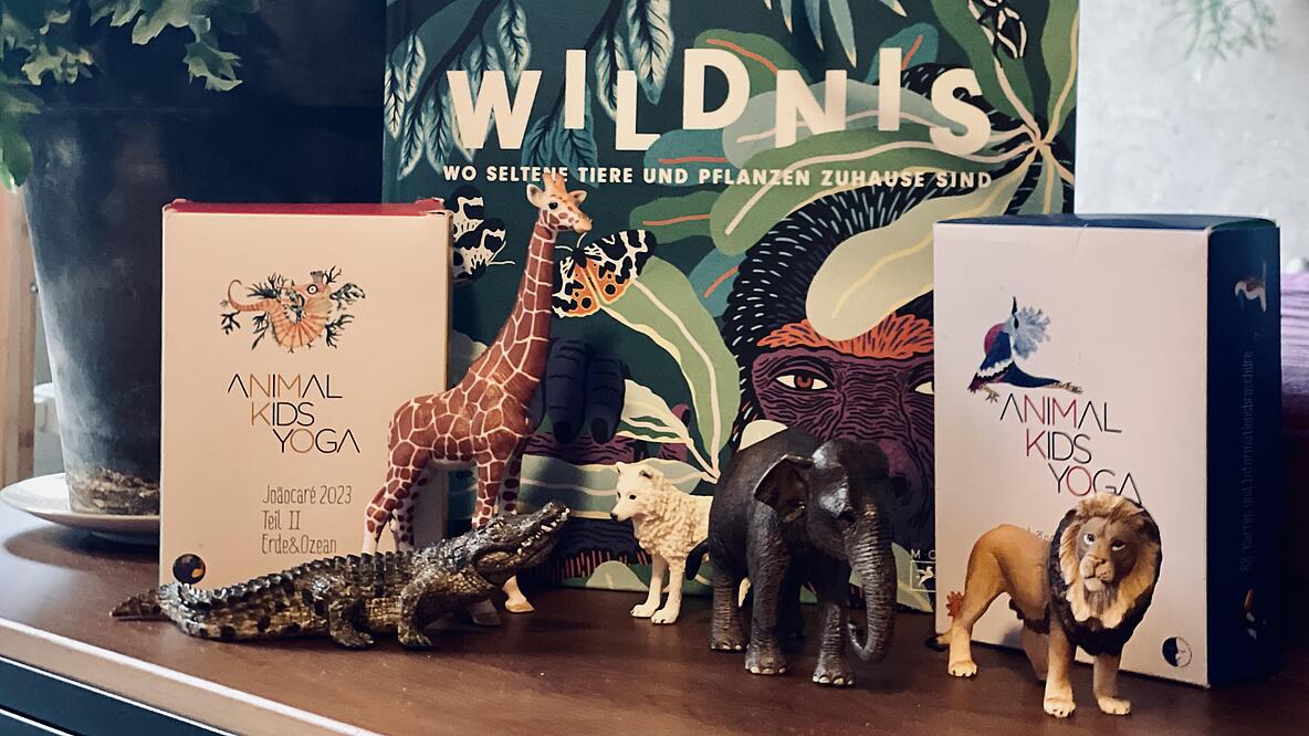 Das Buch Wildnis, daneben Tierfiguren und Yoga-Karten. 