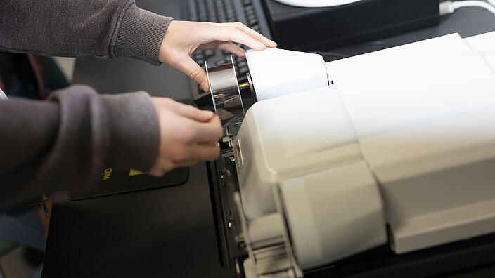 Hände bedienen ein Mikrofilmlesegerät