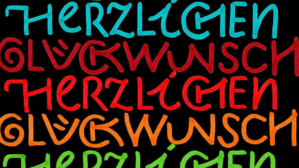 Bunte Schrift "Herzlichen Glückwunsch" auf schwarzem Hintergrund. 