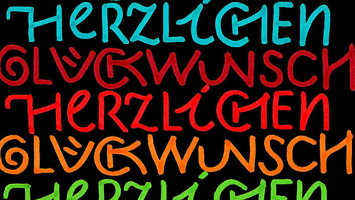 Bunte Schrift "Herzlichen Glückwunsch" auf schwarzem Hintergrund. 