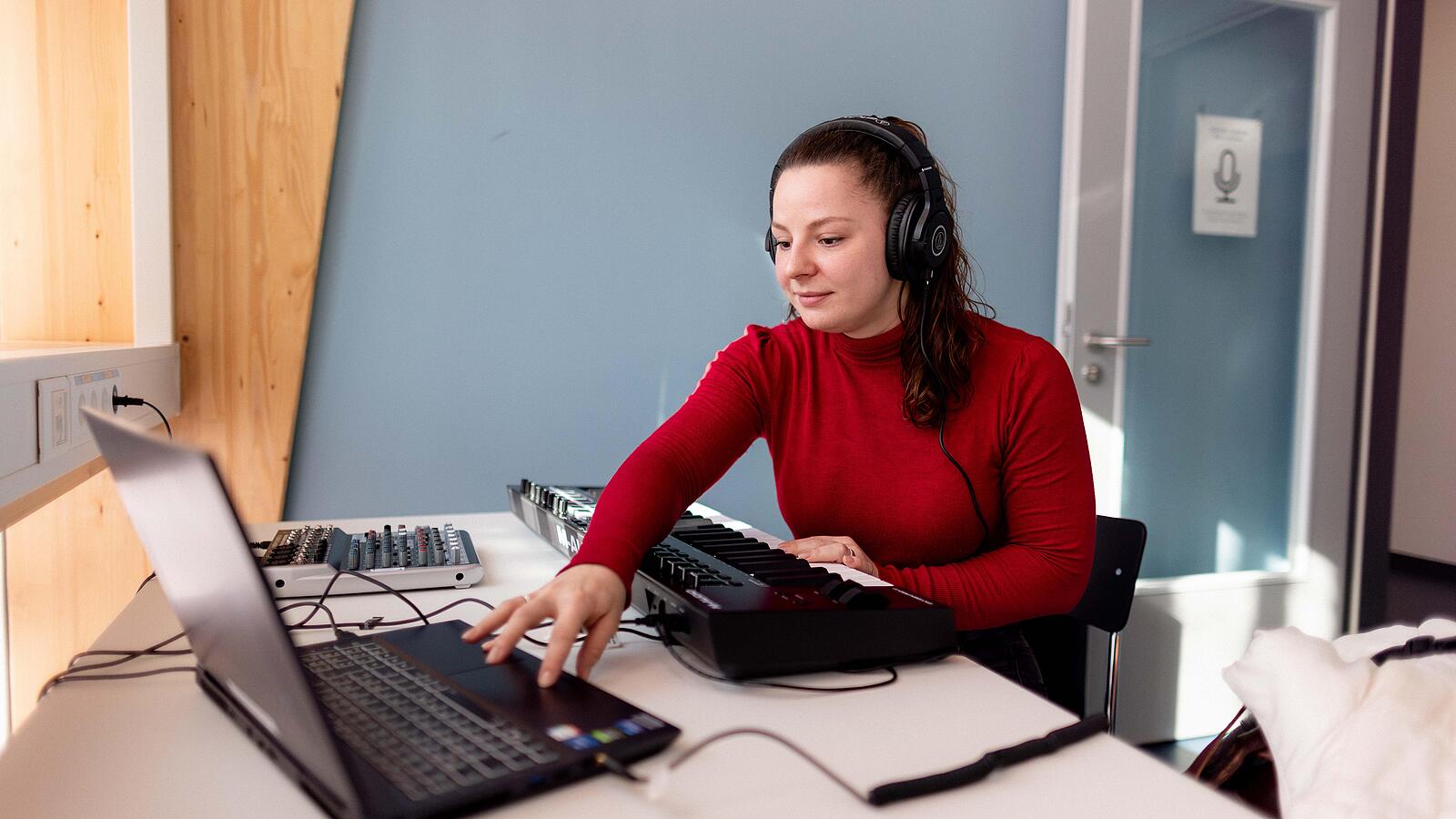 Man sits at desk with headphones and speaks into microphone in front of small camera