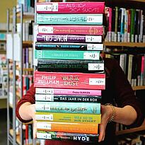 Die FSJlerin Paula hät einen Stapel Bücher vor sich, der das gesamte Bild ausfüllt
