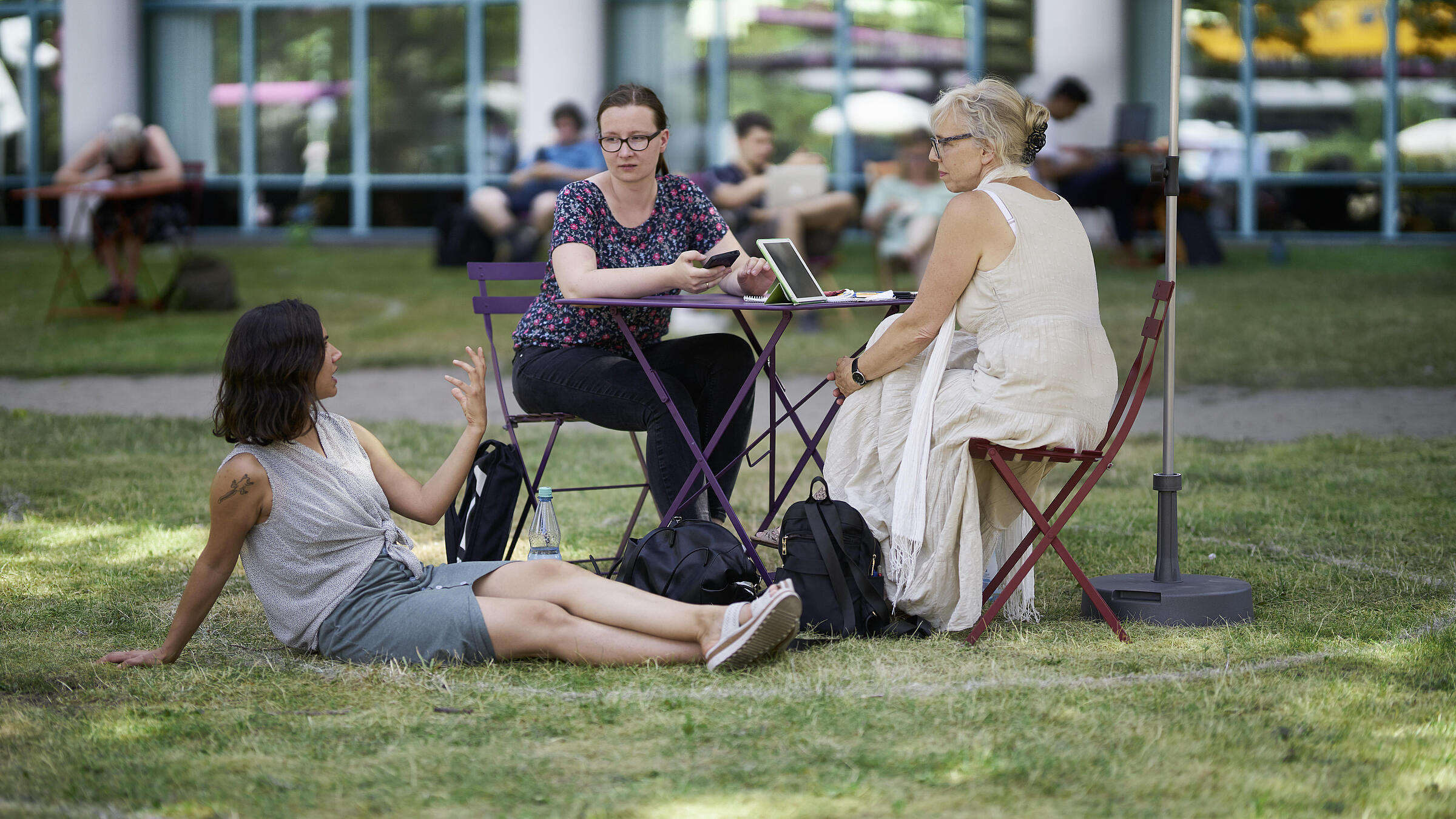 Group of 3 people sitting at table on the lawn in front of the AGB