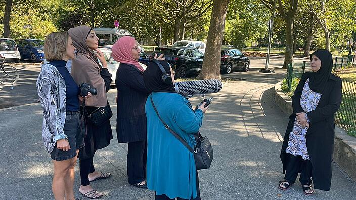 Drei Frauen mit Kopftuch und eine ohne Kopftuch interviewen eine Frau mit Kopftuch vor der AGB-Frischluftbibliothek 