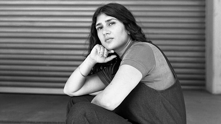 Schwarz-weiß Portrait der Person Fatma Aydemir, die lässig auf dem Boden hockt