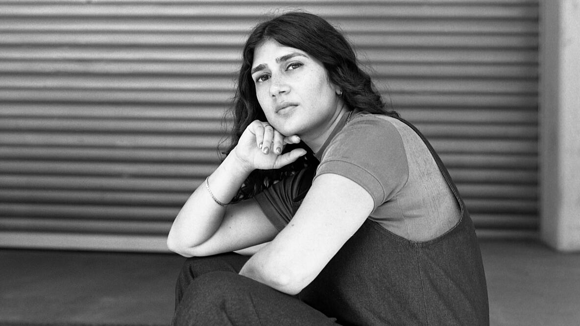 Schwarz-weiß Portrait der Person Fatma Aydemir, die lässig auf dem Boden hockt