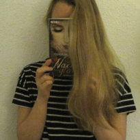 Die FSJlerin Sarah hält ein Buch mit Gesicht vor Ihr eigenes Gesicht und lässt die Haare darüber fallen