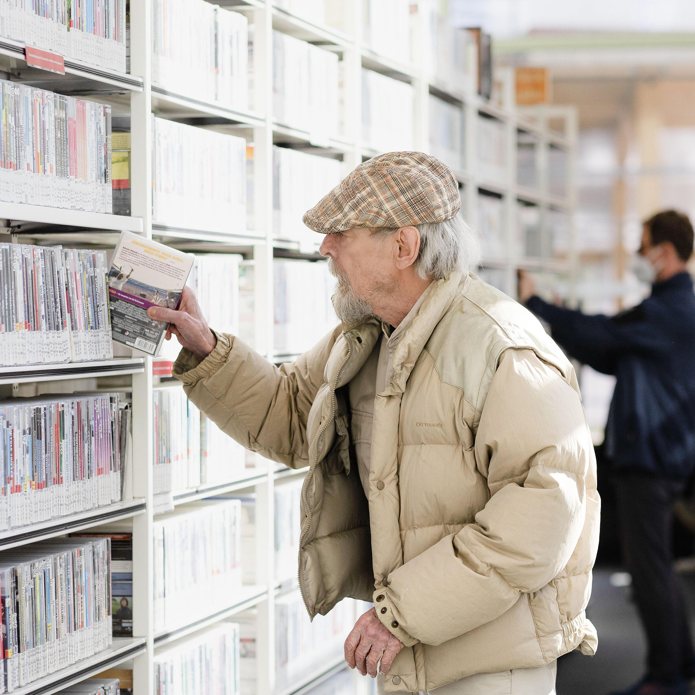 Älterer Herr greift DVD aus dem Regal der Cinemathek