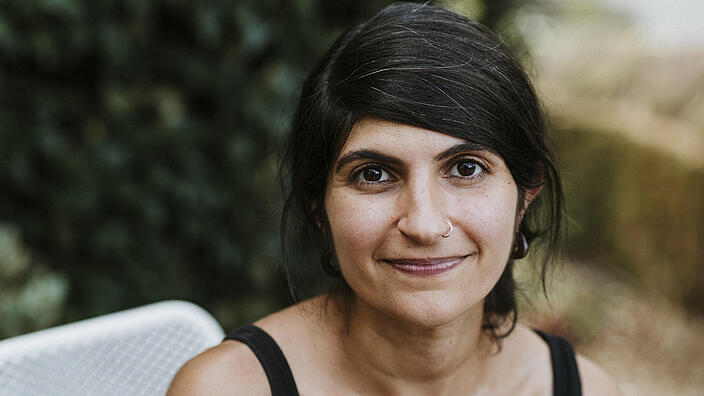 Portrait einer lächelnden Person vor verschwommenem Hintergrund