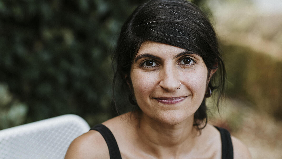 Portrait einer lächelnden Person vor verschwommenem Hintergrund