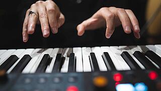 Foto mit Nahaufnahme von klavierspielenden Händen