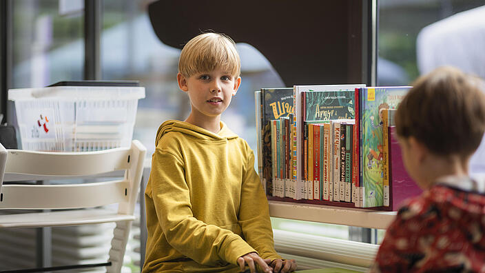 Junge sitzt an Spielebox vor Büchern in der KiJuBi