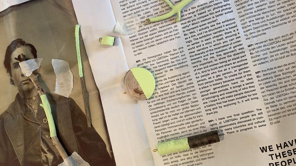 auf eine Zeitung mit Kreppband geklebte Holzstücke, die teilweise hellgrün bemalt wurden