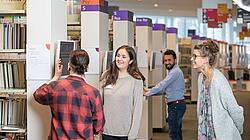 Gruppe junger Menschen steht im Lesesaal der AGB vor einem Katalog-PC und recherchiert nach Büchern