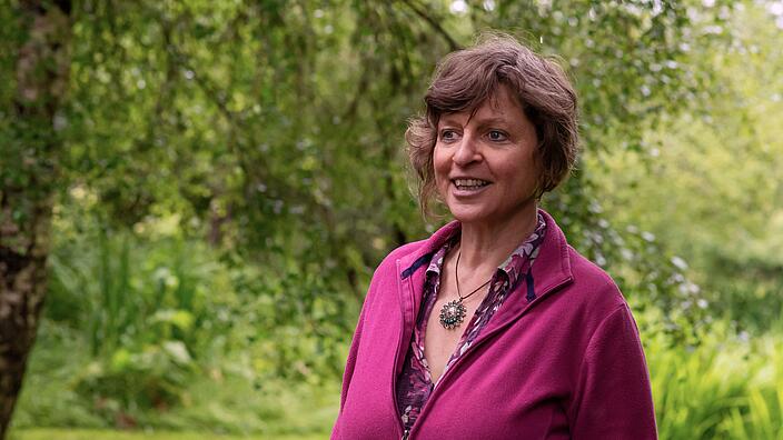 Porträtfoto einer Person vor grüner Landschaft
