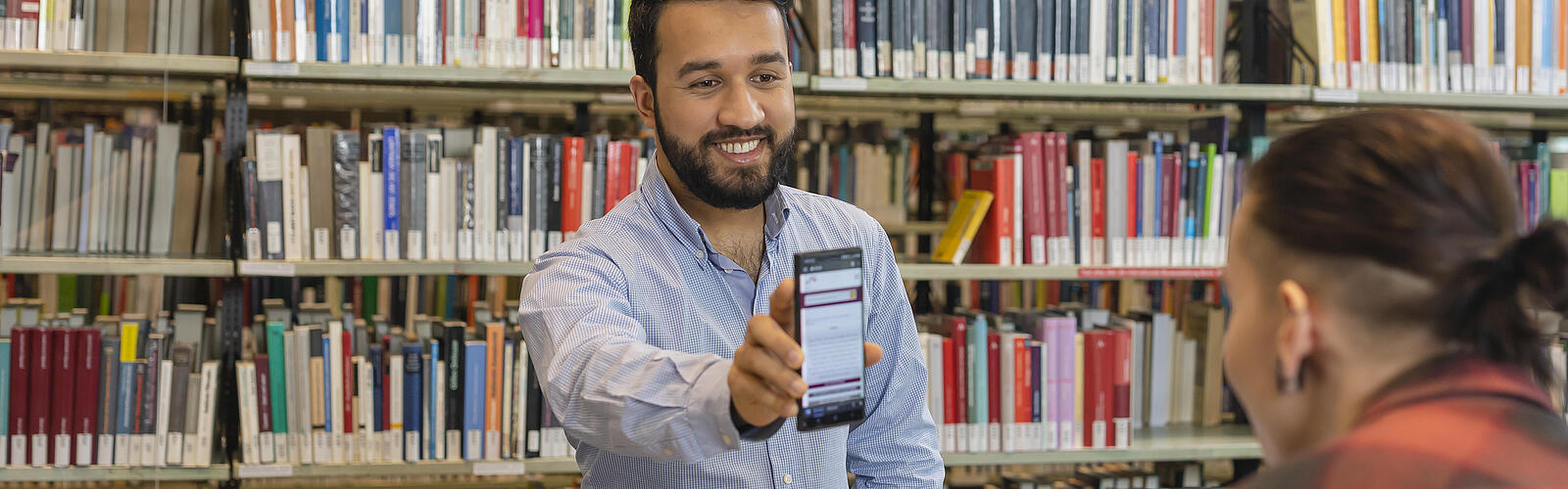 Besucher in der Bibliothek mit einem Handy in der Hand