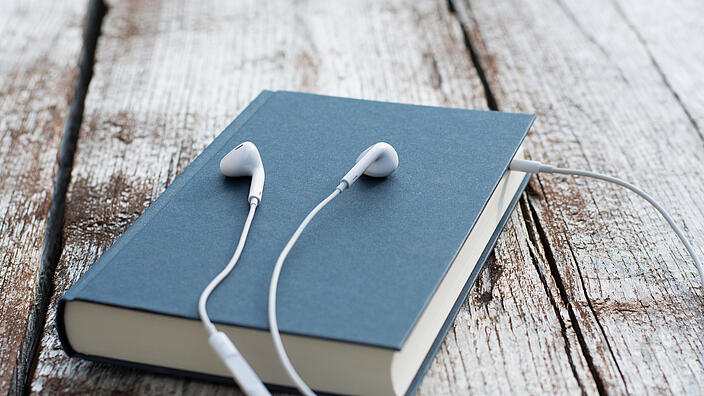 Buch mit iPhone-Kopfhörern die zwischen den Seiten stecken