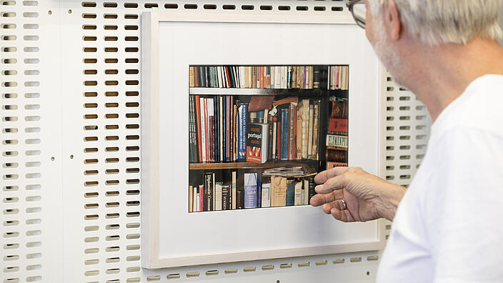 A man in front of artwork in the Artothek of AGB points to the picture