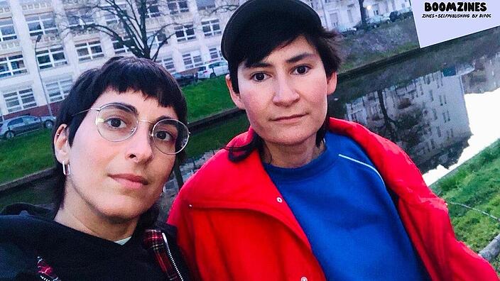 Selfie von zwei Personen, im Hintergrund ein Fluss und eine Häuserfassade
