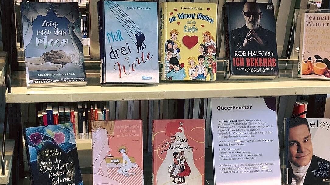 Foto eines Regals mit dem Titel "Queerfenster" und verschiedenen Büchern darauf