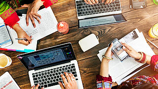 Foto von Händen die auf Papier und Laptops arbeiten