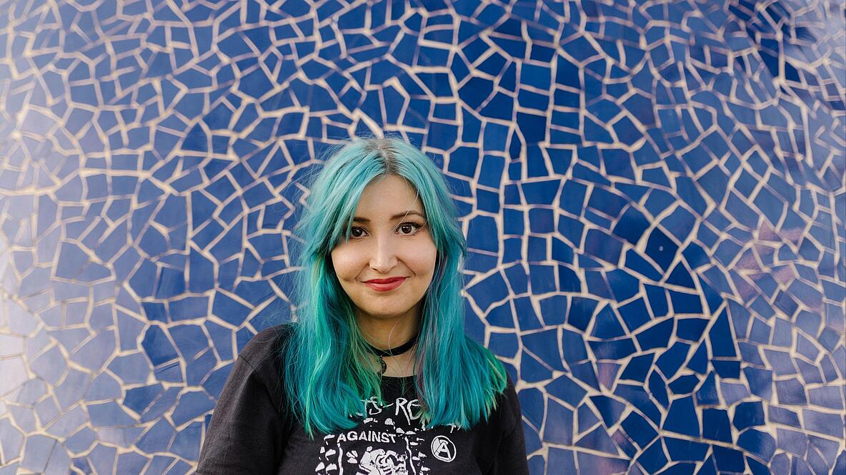 Porträt von Melina Borčak vor blauer Keramikwand
