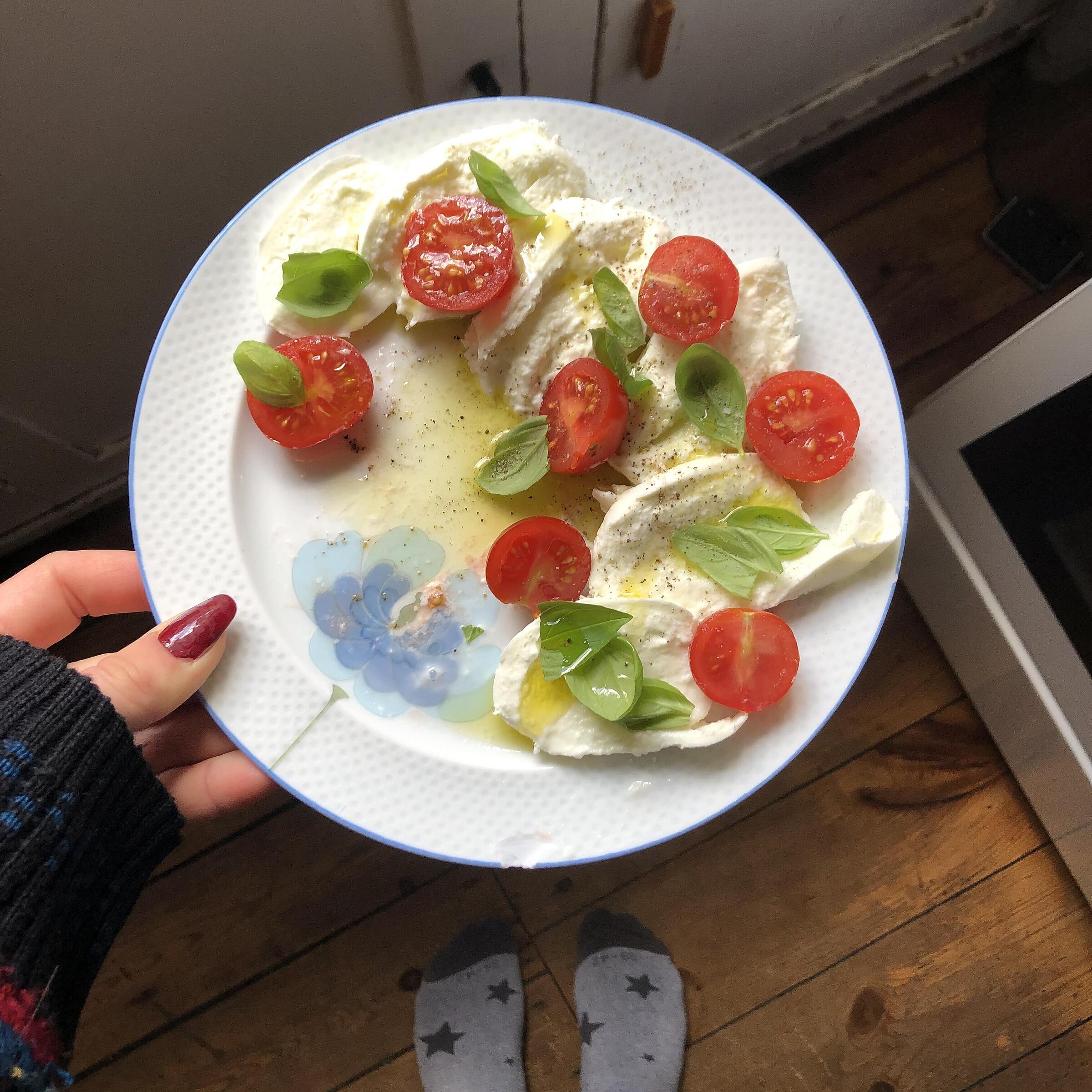 Foto eines Tellers mit Tomaten und Mozzarella, den Milena in der Hand hält