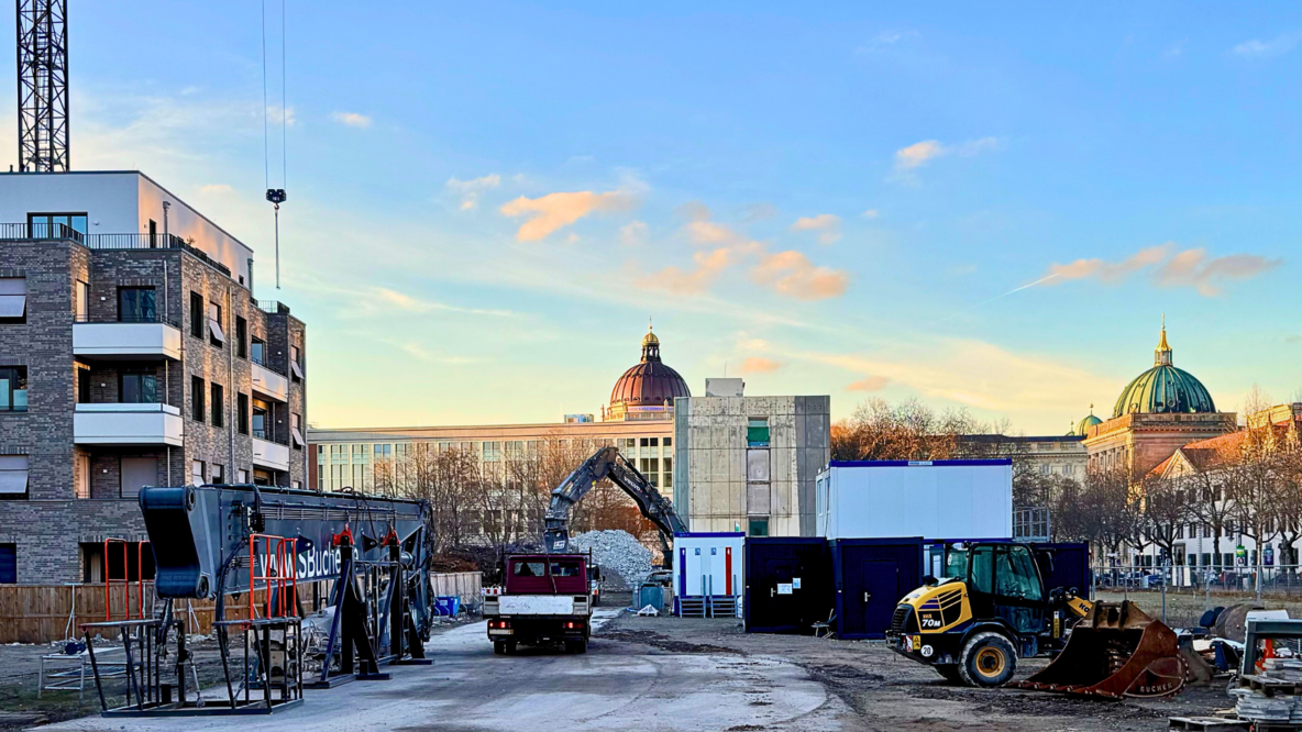 Im Vordergrund eine Baustelle in Berlin-Mitte, die Kuppeln des Berliner Stadtschlosses und des Berliner Doms im Hintergrund