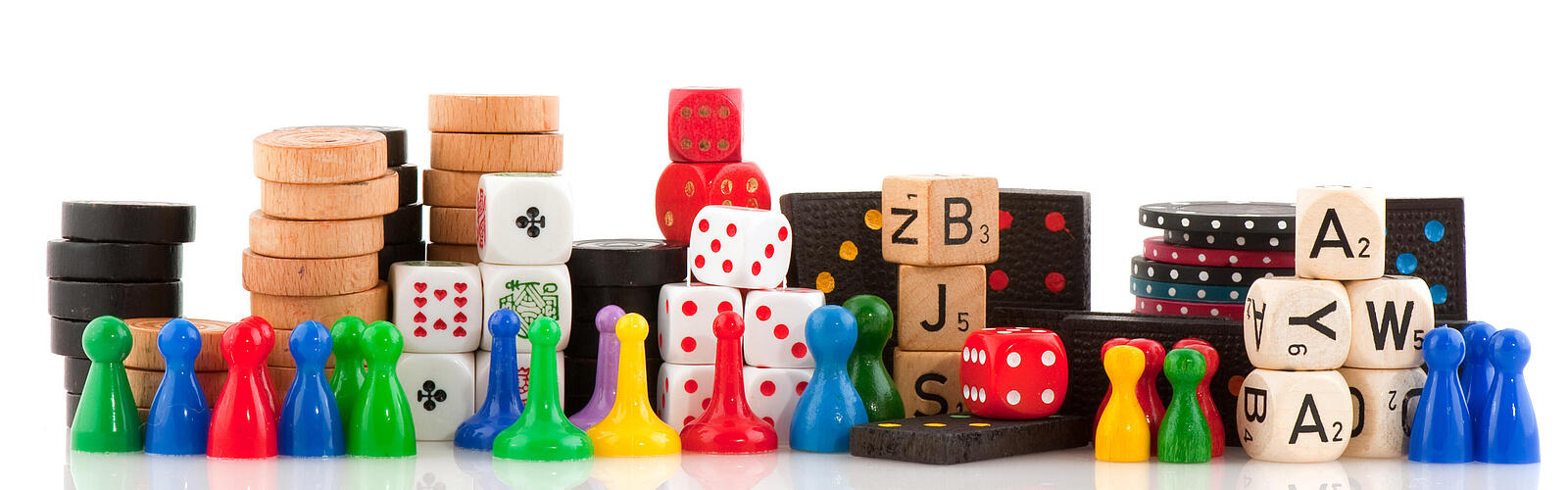 Verschiedene Spielfiguren, Chips und Würfel vor einem weißen Hintergrund