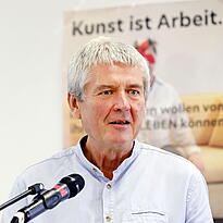 Andreas Köhn steht am Rednerpult mit einem Mikro