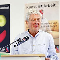 Andreas Köhn steht am Rednerpult mit einem Mikro