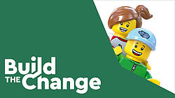 Eine LEGO Figur mit braunem Zopf und eine LEGO Figur mit blauer Kappe schauen freundlich um eine grüne Ecke.