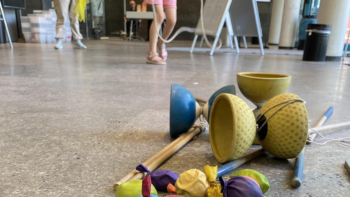 Jonglierbälle und Diabolos auf dem Boden ligend mit seispringenden Kindern im Hintergrund