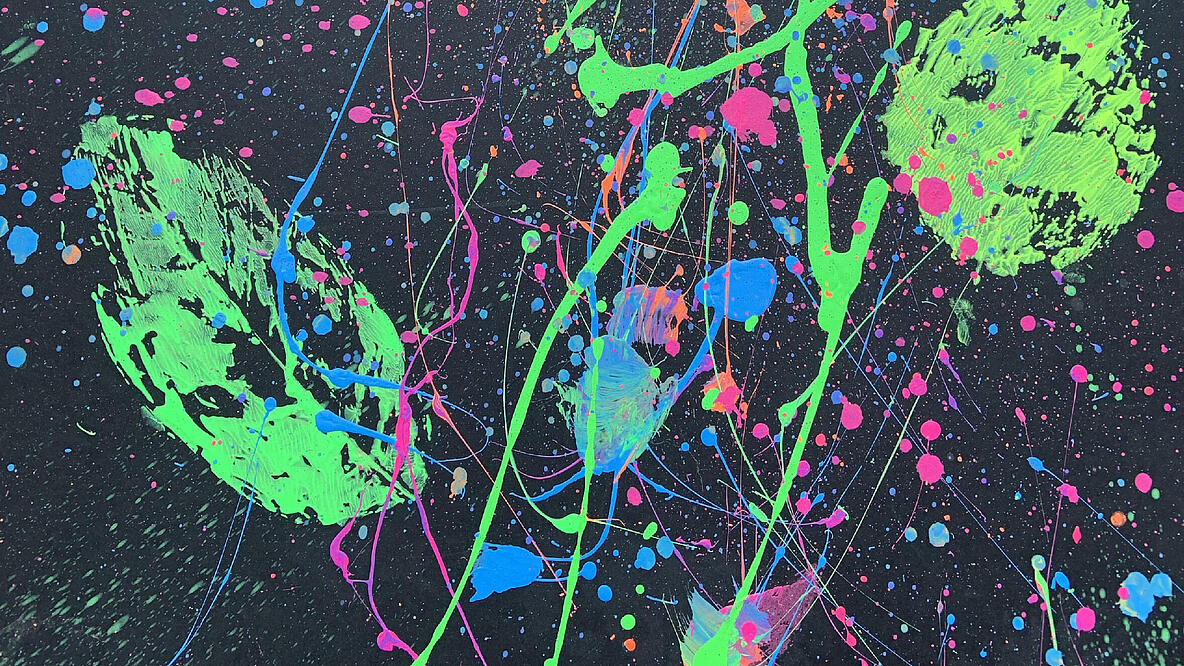 Abdrücke von Baumblättern in Neonfarben mit Farbspritzern auf schwarzem Papier