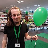 Der FSJler Niko mit grünem Luftballon in der Hand in der KiJuBi