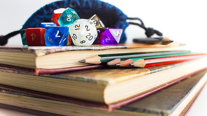 Bücher, verschiedene Würfel und Stifte die Dungeons and Dragons symbolisieren sollen