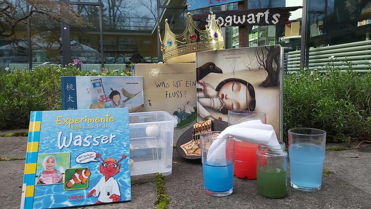 Foto von Kinderbüchern neben Gläsern mit bunter Flüssigkeit