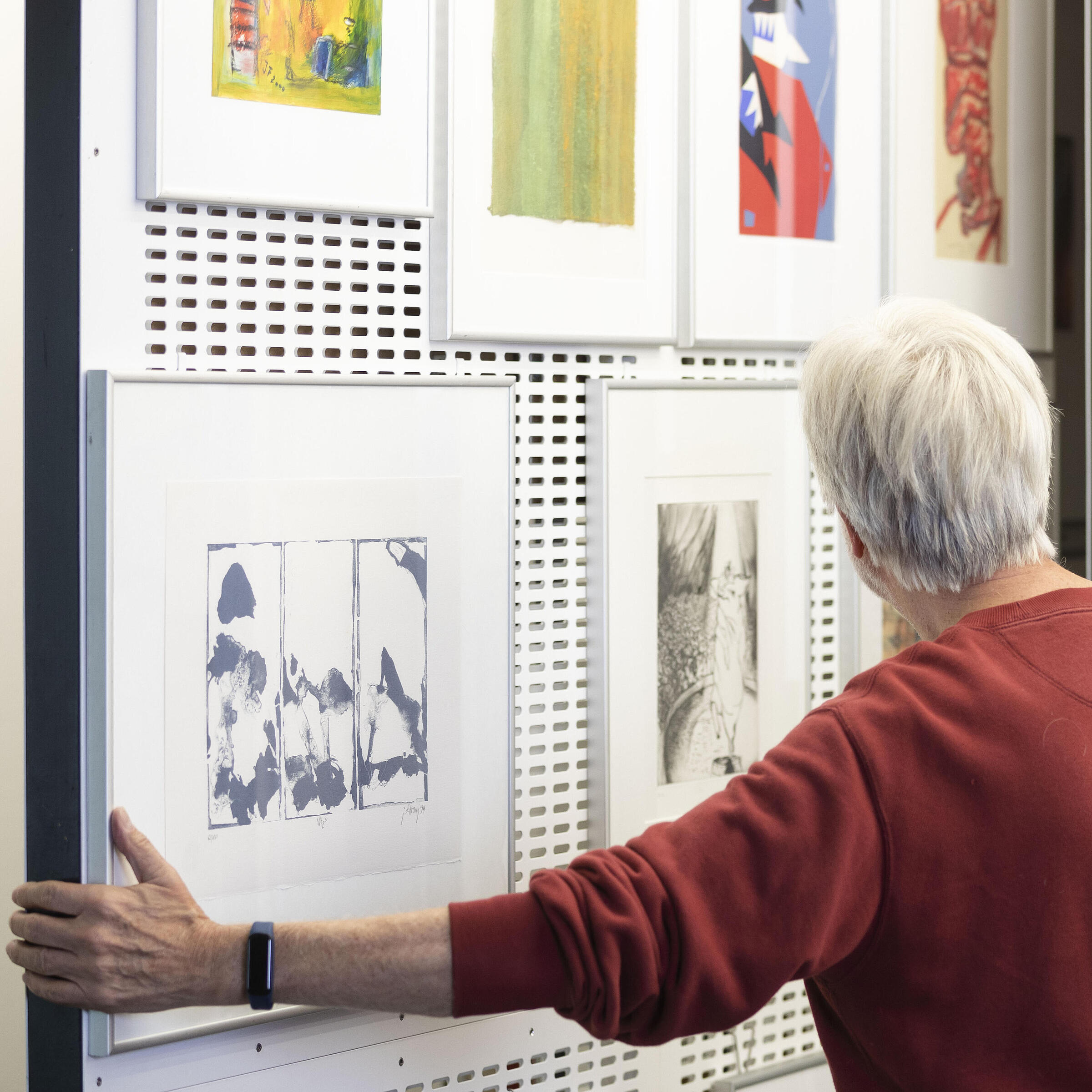 Elderly man in the Artothek in the AGB has pulled out the pull-out shelf and is looking at the artworks