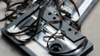 Eine Kompaktkassette mit herausgezogenem Tonband.