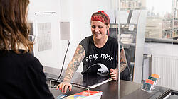 Foto von einer Person, die an der Servicetheke in der Bibliothek der Kundin die Bücher verlängert