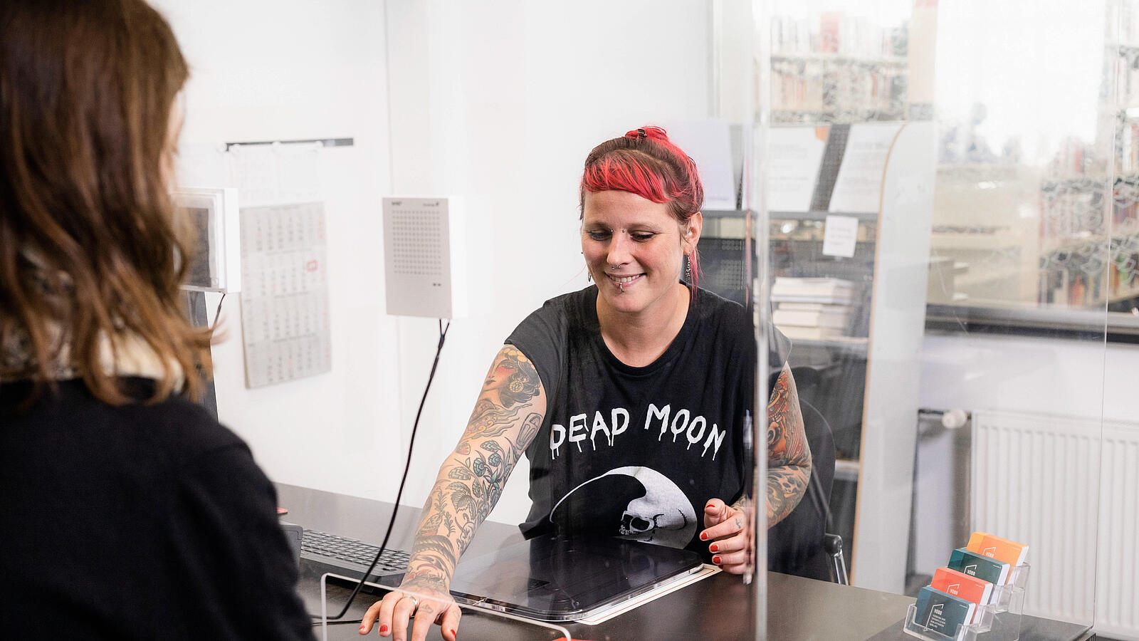 Foto von einer Person, die an der Servicetheke in der Bibliothek der Kundin die Bücher verlängert