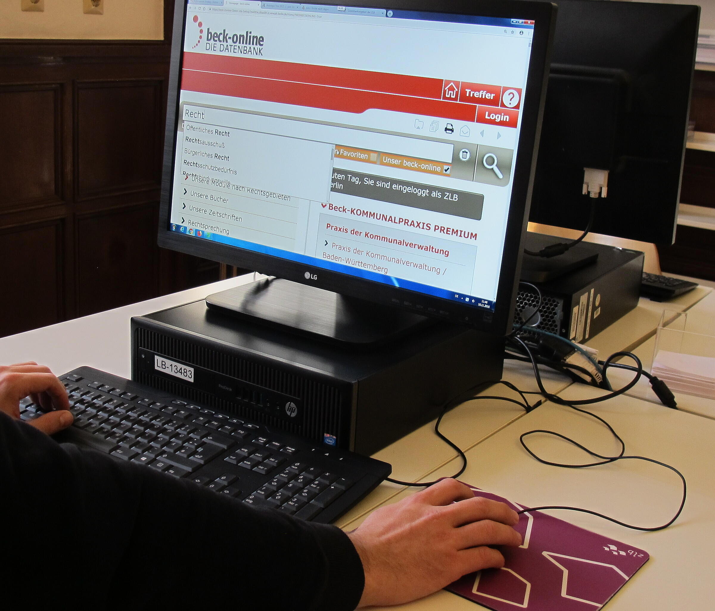Mensch hat seine Hände auf Tastatur und Maus, während er auf Computerbildschirm blickt bei geöffneter Datenbank Beck Online