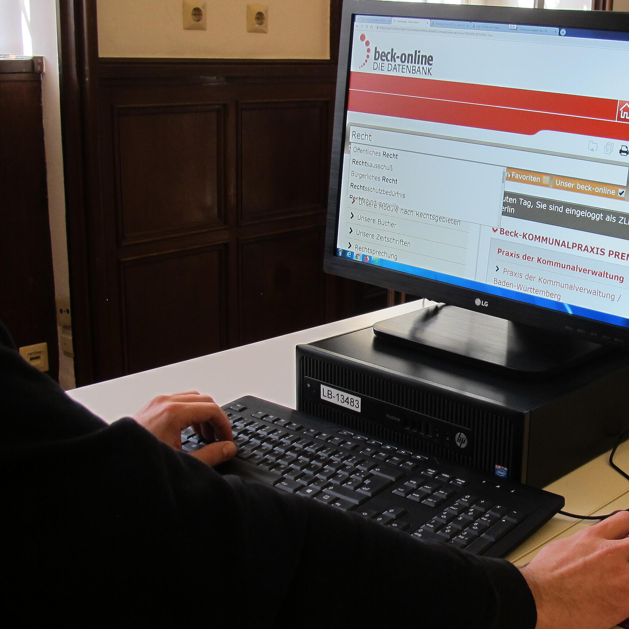 Man has his hands on keyboard and mouse while looking at computer screen with open database Beck Online