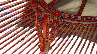 Innenfoto der Jurte mit Fokus auf die Balkenschnitzerei im Dach