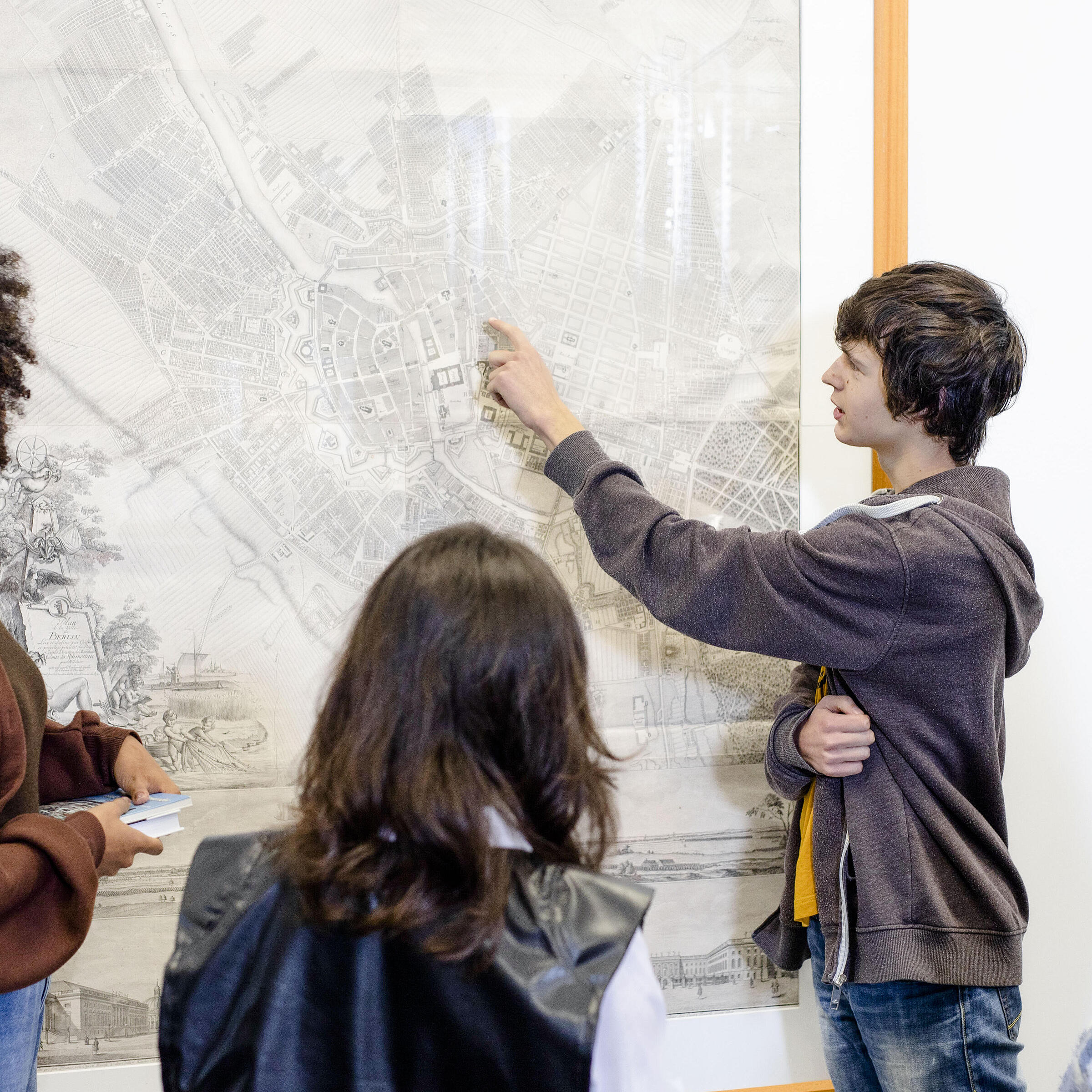 Young people look at a historical map in the Berlin collections of the BStB