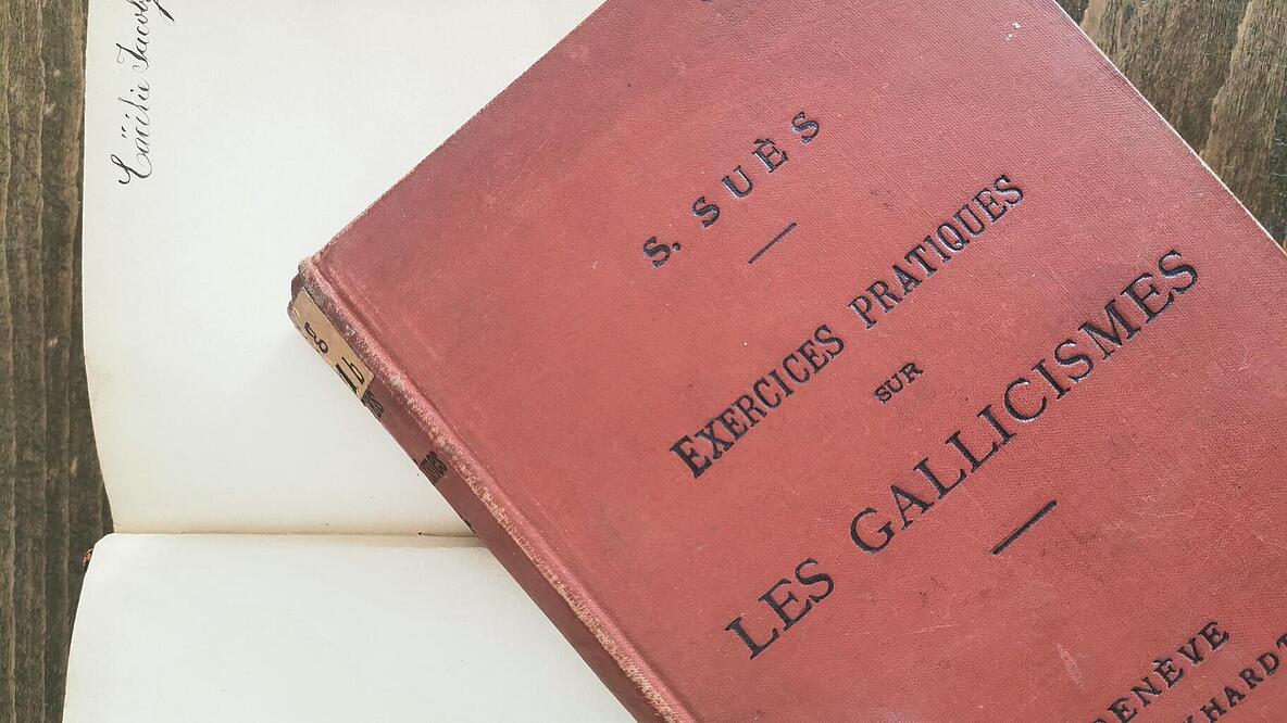 Foto von altem, rotem Buch mit dem Titel: Les Gallicismes und aufgeschlagendes Buch im Hintergrund mit Autogramm von Cäcilie Holländer, geb. Jacoby
