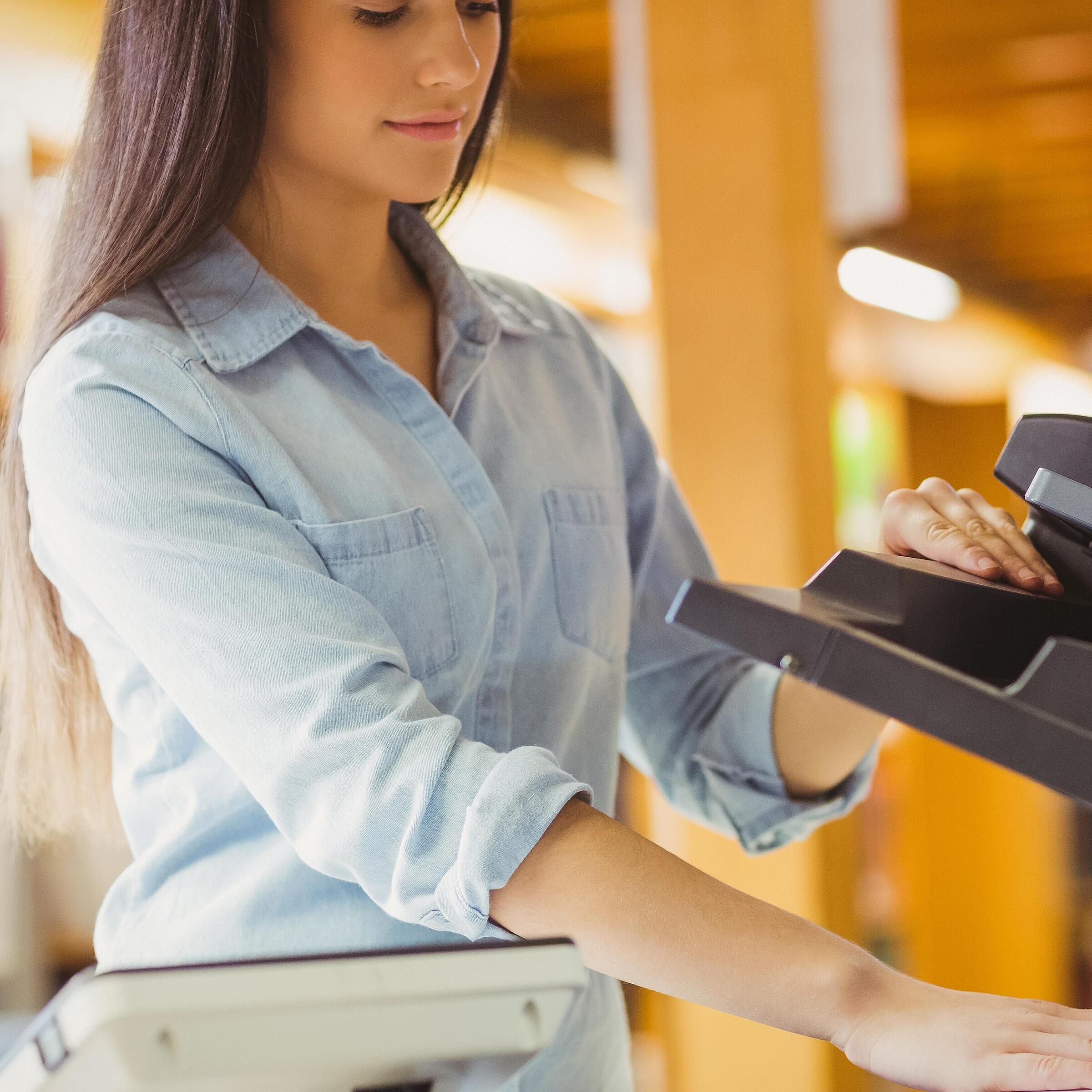 Young woman puts a book in a photocopier