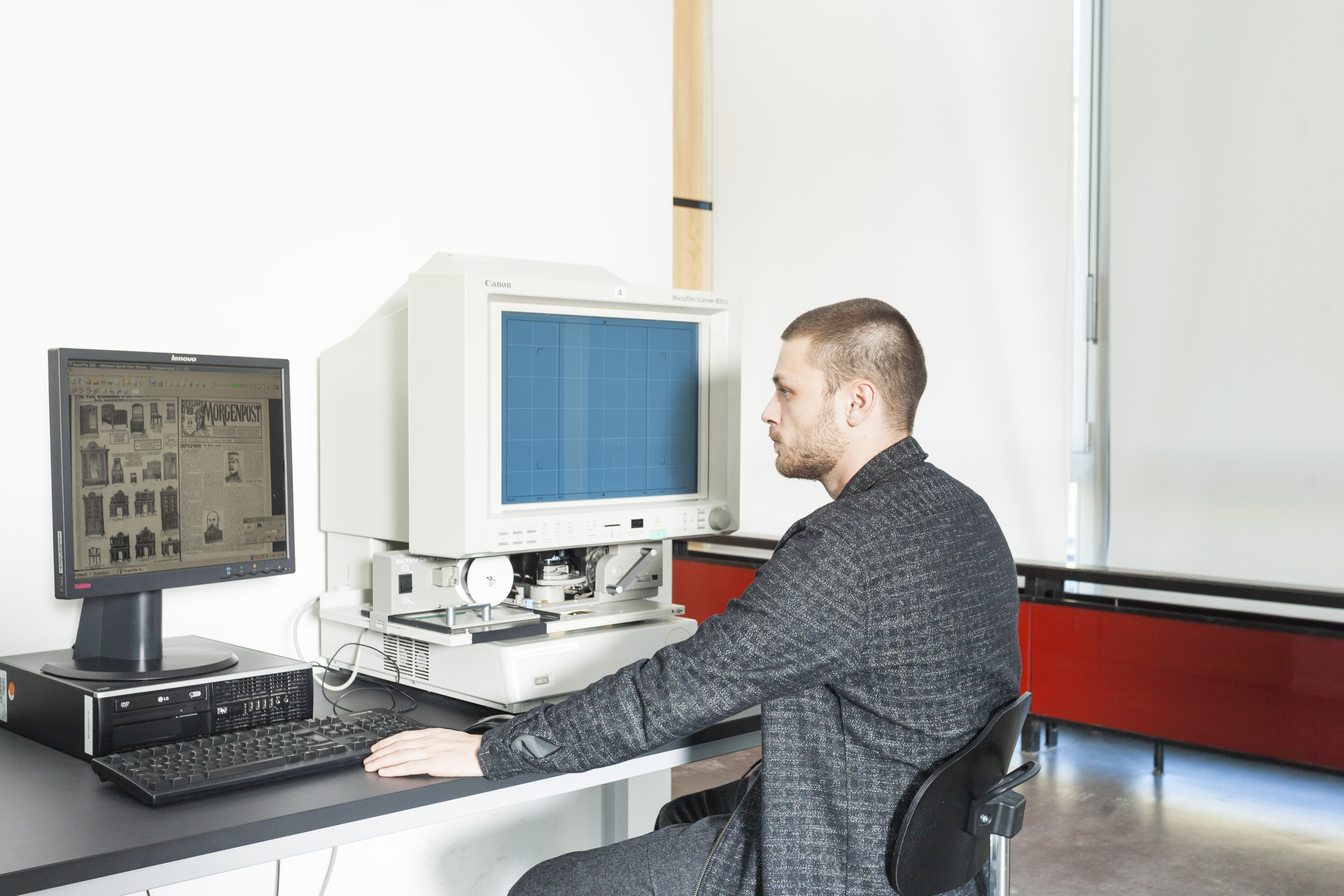 Junger Mann sitzt an Mikrofilmlesegerät in der BStB und recherchiert