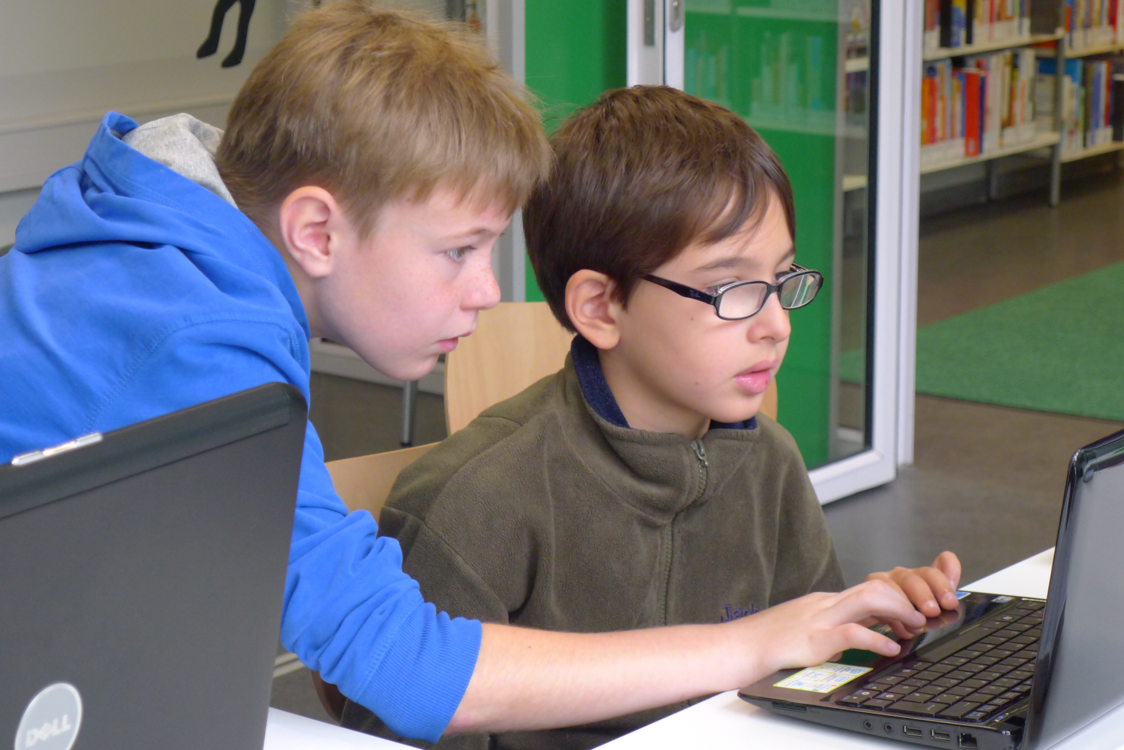 Zwei kleine Jungs gucken gemeinsam auf Laptop in der KiJuBi